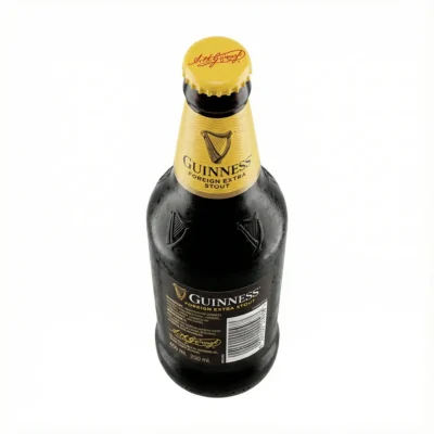 Vue de dessus de la BIERE EN BOUTEILLE PETITE GUINNESS 33CL, en verre noir avec une étiquette et une capsule jaunes.