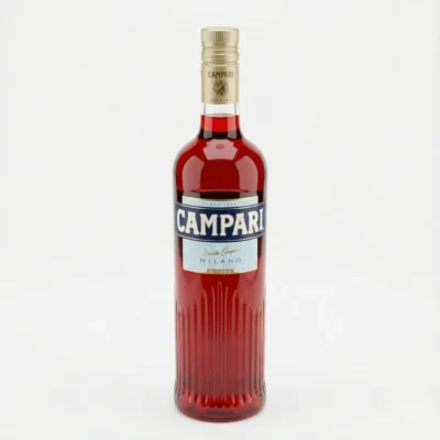 Vue de face de la bouteille en verre cannelée de CAMPARI 1 l, avec sa liqueur rouge, son étiquette bleue et son bouchon doré.