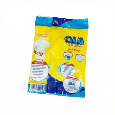 Vue de arrière du sachet de DETERGENT OLA 25G, emballage plastique jaune et bleu montrant les ingrédients et le code-barres.