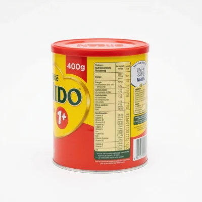 Vue de côté de la boîte en métal rouge et jaune du lait en poudre NIDO 1+ de Nestlé, affichant l'étiquette nutritionnelle.