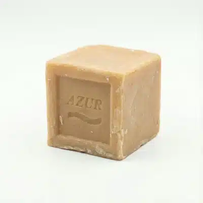 Vue de latérale du Savon Azur 350g, un bloc cubique de savon traditionnel beige rustique sur un fond blanc.