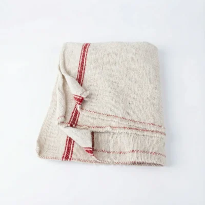 Vue de dessus d'une serpillière pliée en coton écru à rayures rouges, au tissage épais et texturé sur fond blanc.