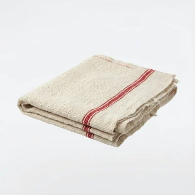 Vue de latérale d'une serpillière en coton écru pliée, ornée de deux bandes rouges, sur un fond blanc.